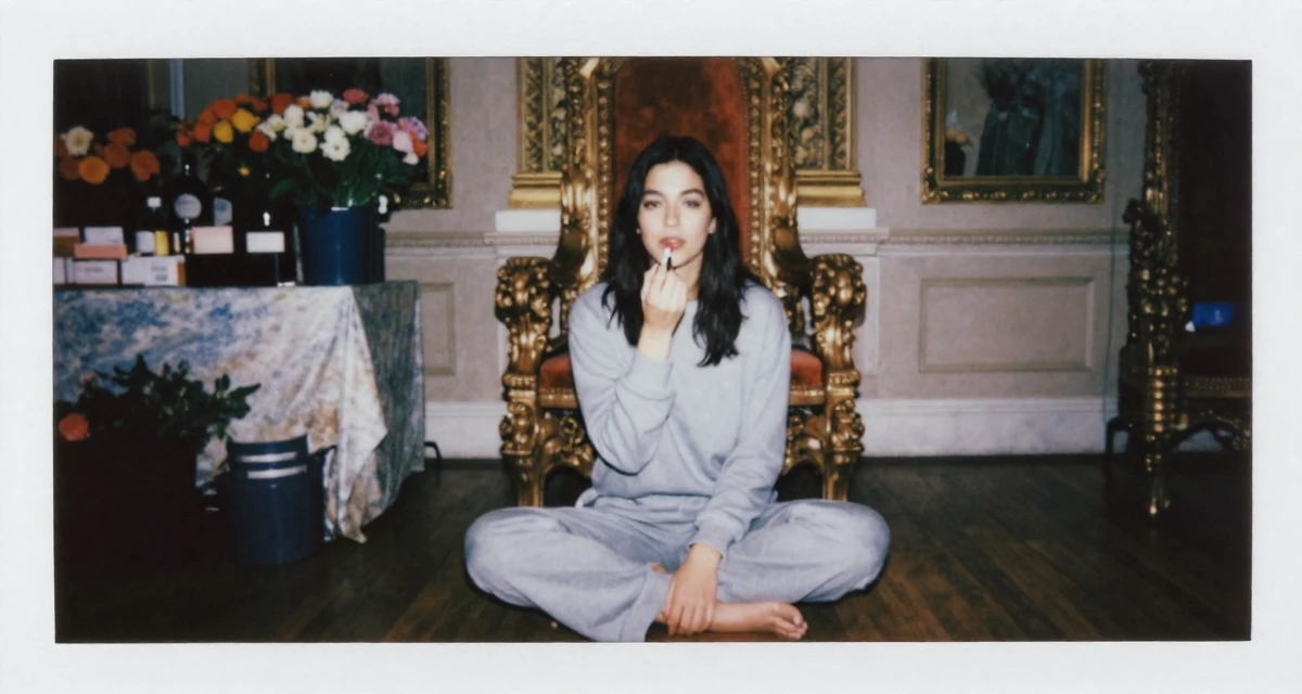 A composed Female From USA, majored in communications at a state university in their 28, recovering from a failed startup, wearing a comfortable lounge wear set, applying lipstick in a royal palace throne room.