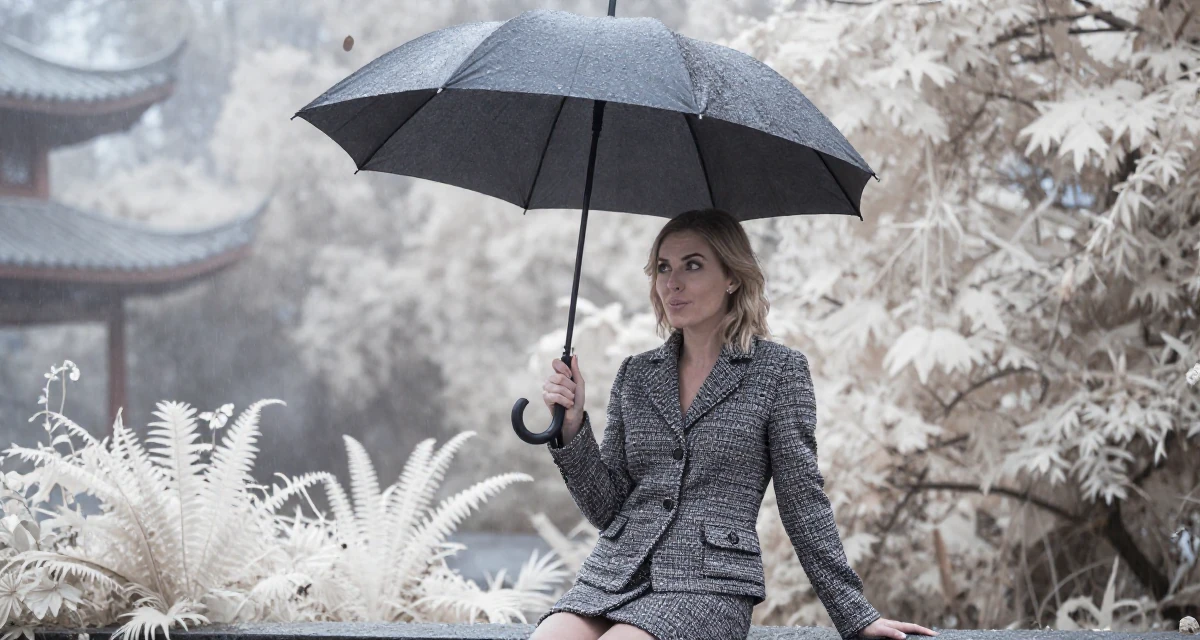 A teasing Female From Canada, trained in culinary arts in their 22, exploring early career opportunities, wearing a classic chanel style tweed suit, shaking rain off an umbrella in a dense misty forest.