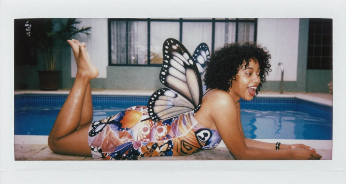 A spirited Female From Kenya, based in Nairobi, graduated from a creative institute majoring in aesthetic communication in their 48, finding purpose beyond motherhood, wearing a butterfly-themed fairy dress with large wings, reaching for a pocket in a swimming pool.