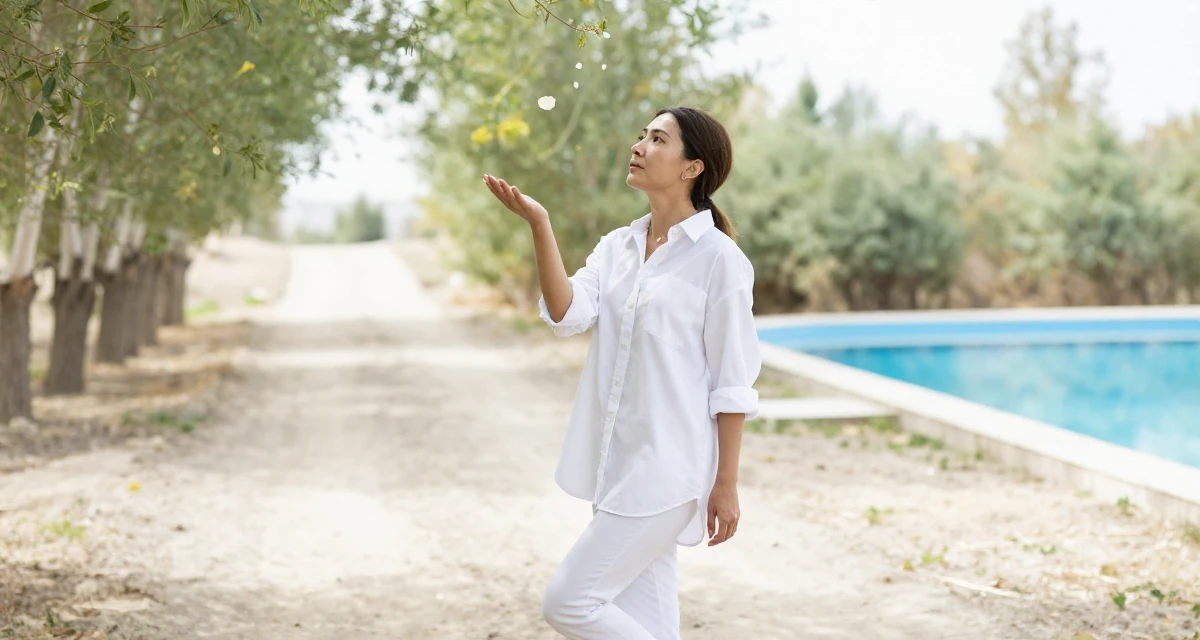 A introspective Female From Kyrgyzstan, majored in public health in their 32, sharing budget-friendly interior design tips, wearing a oversized white shirt with sleeves rolled up and slim trousers, catching a falling flower petal in a magical forest clearing.