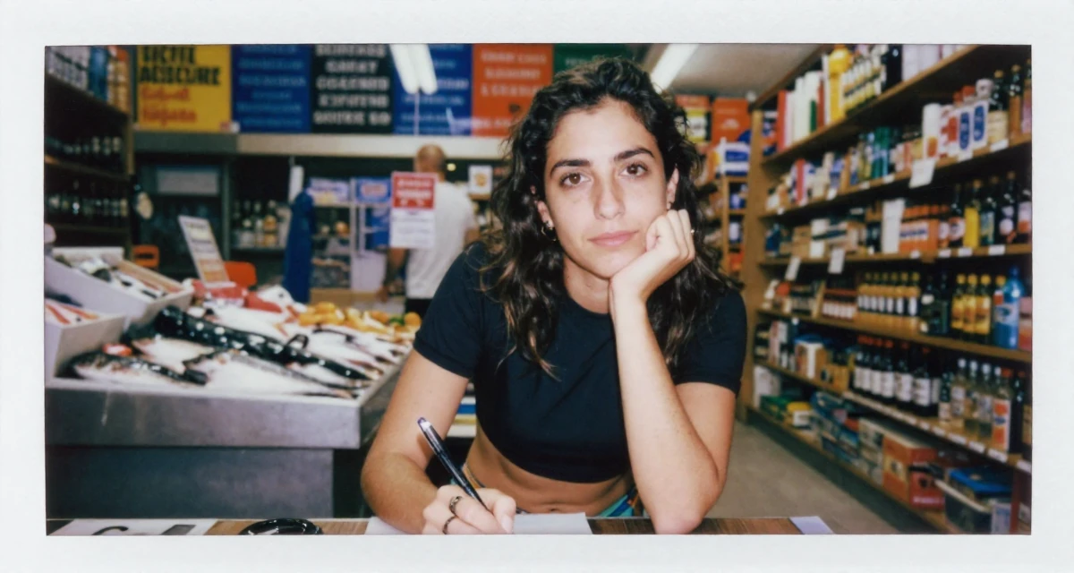 A quietly confident Female From Spain, majored in public relations and advertising in their 38, single dad sharing parenting hacks, wearing a cropped rash guard and bikini bottom, holding a pen poised to write in a bookstore aisle.