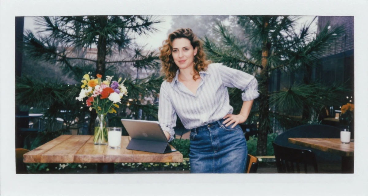 A grateful Female From Netherlands, studied media and culture in their 34, ex-corporate lawyer turned yoga instructor, wearing a striped button-down shirt tucked into a denim pencil skirt, holding a tablet device in a cozy café.